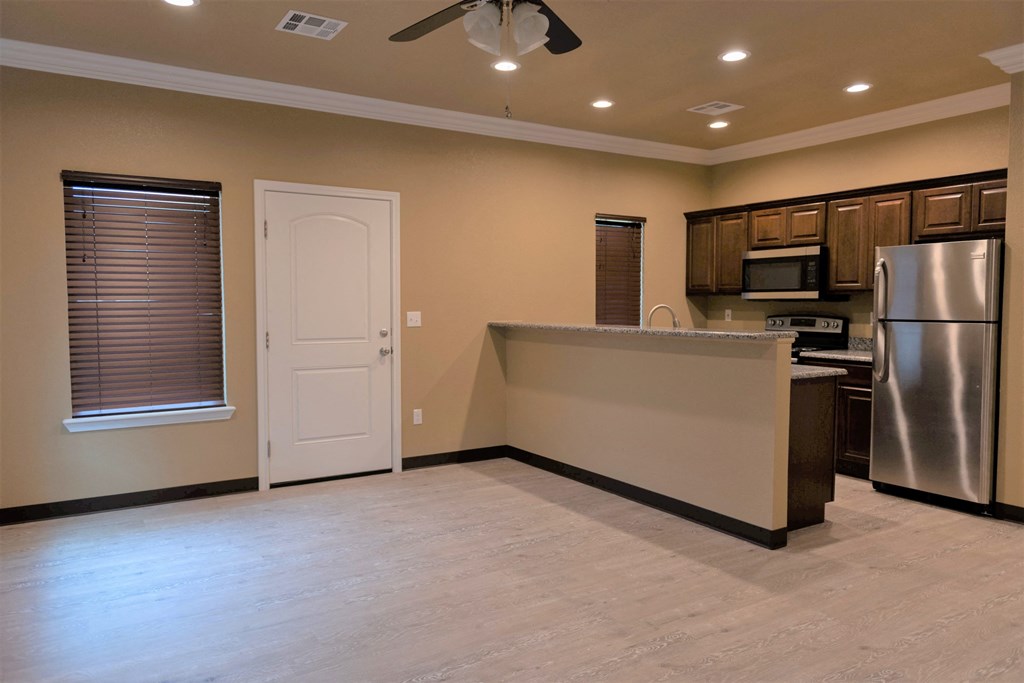 an empty kitchen with a stainless steel refrigerator and a sink