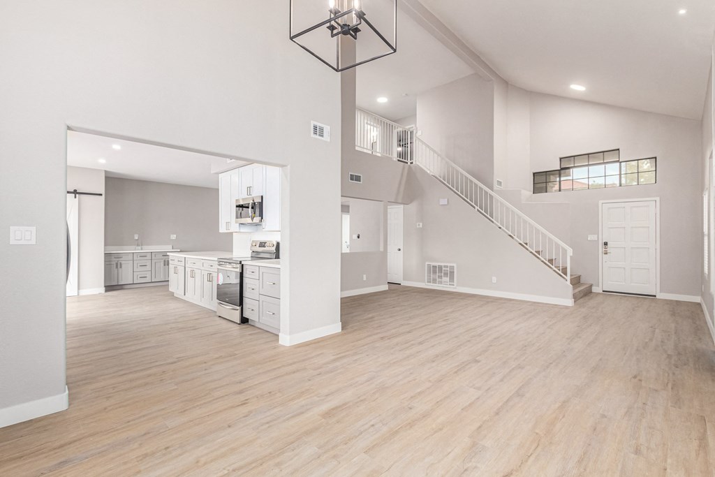 the living room and kitchen of a new home with white walls and wood flooring