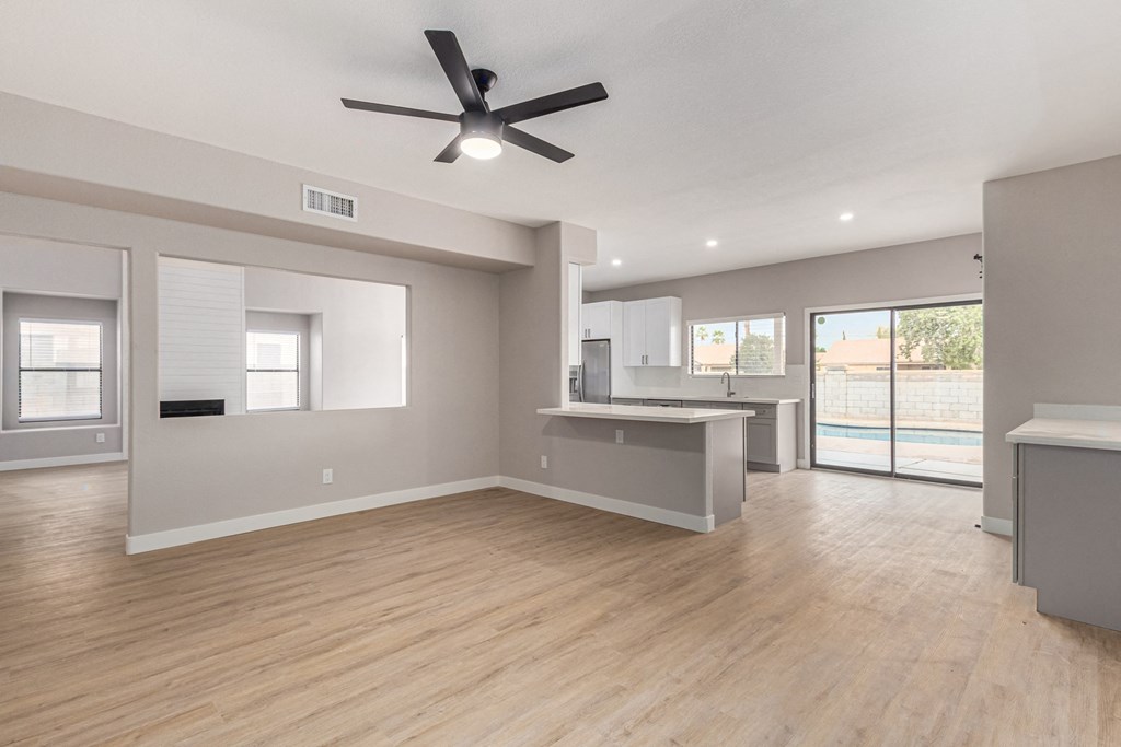 an empty living room and kitchen with a ceiling fan