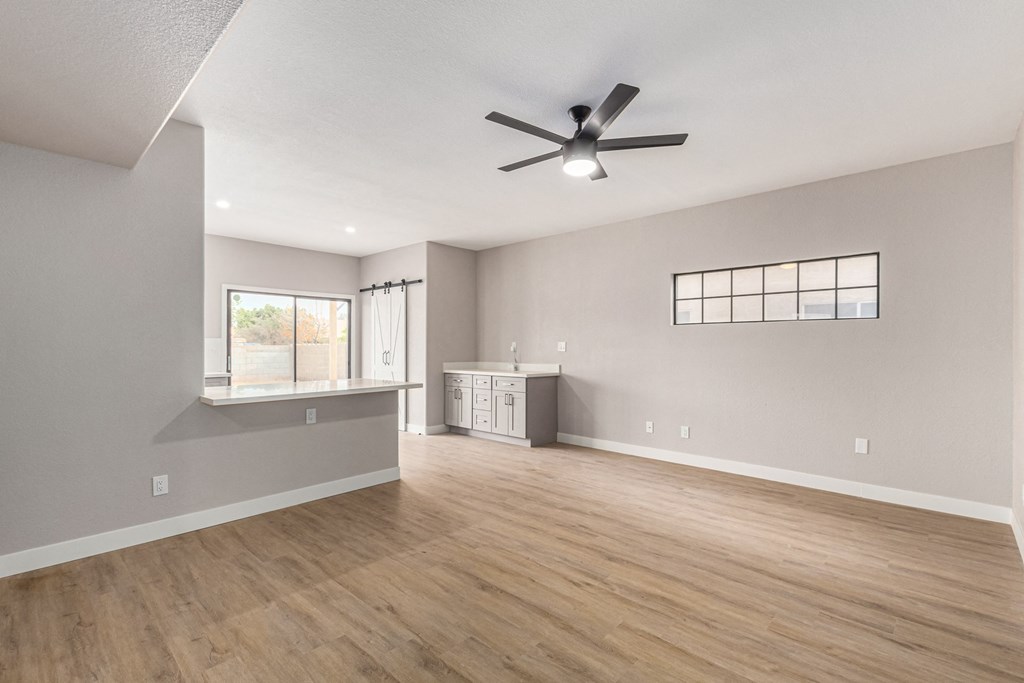 the living room and kitchen of an empty house with a ceiling fan