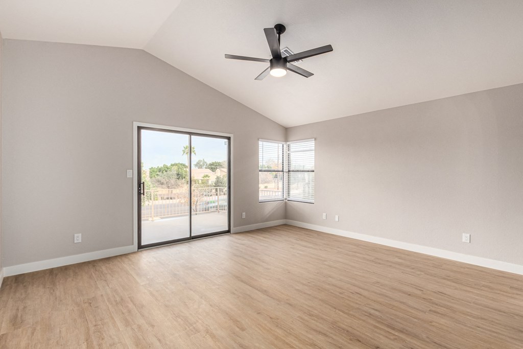 an empty living room with a ceiling fan and a sliding glass door