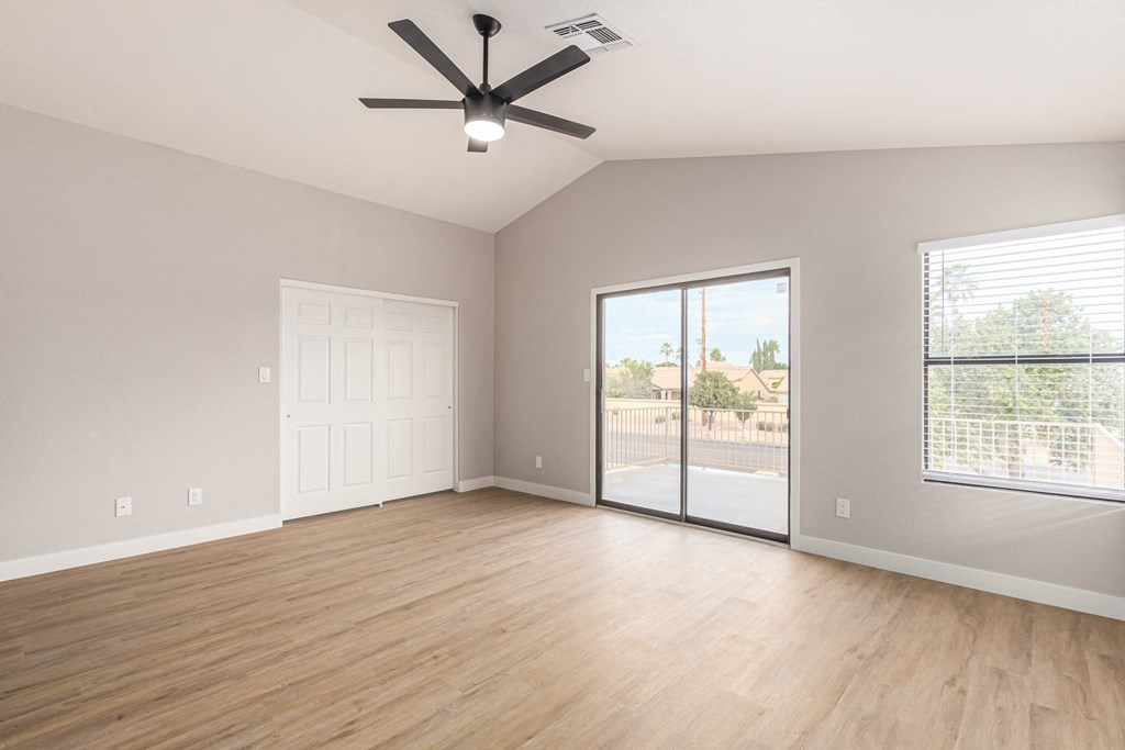 an empty living room with a ceiling fan and a sliding glass door
