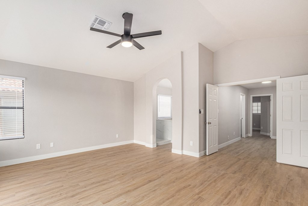 an empty living room with a ceiling fan