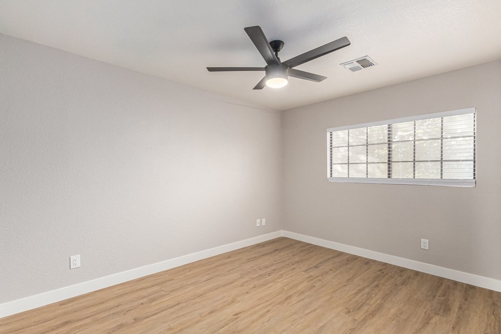 an empty living room with a ceiling fan and a window