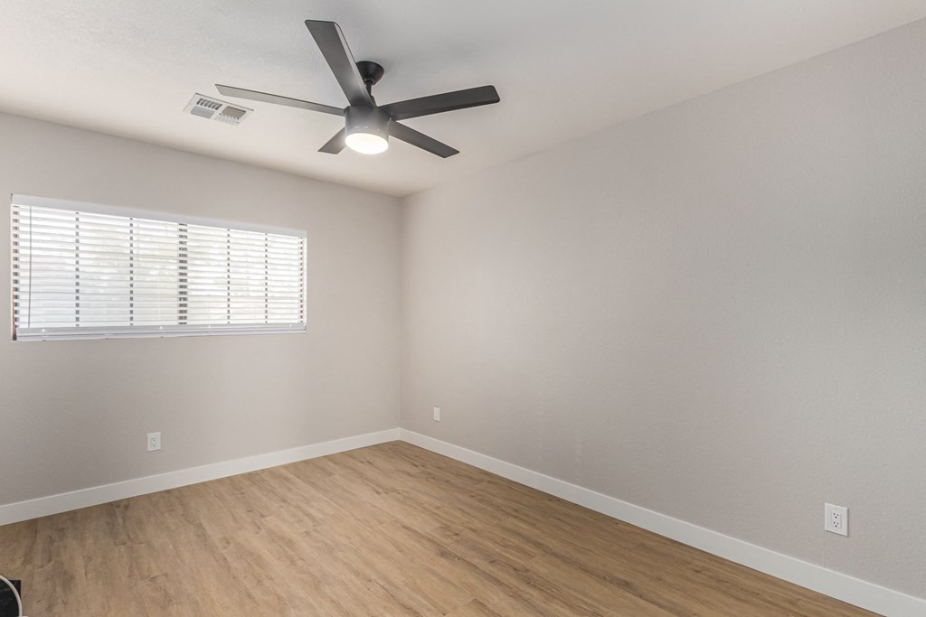 an empty living room with a ceiling fan and a window
