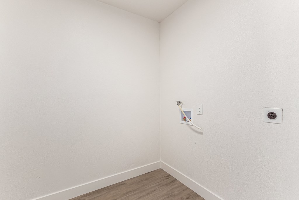 an empty room with a white wall and a white electrical outlet