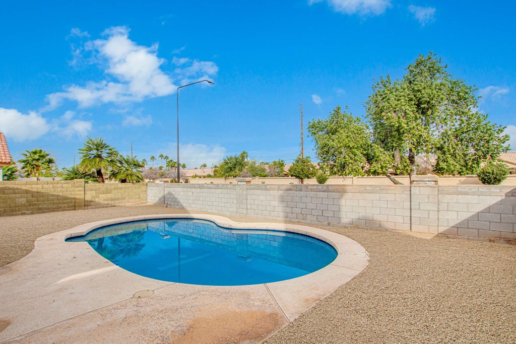 a swimming pool in the backyard of a house with a blue sky