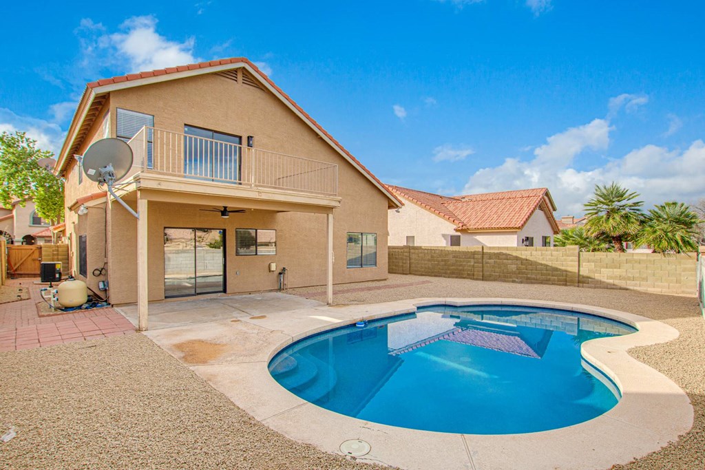 a backyard pool with a house and a pool