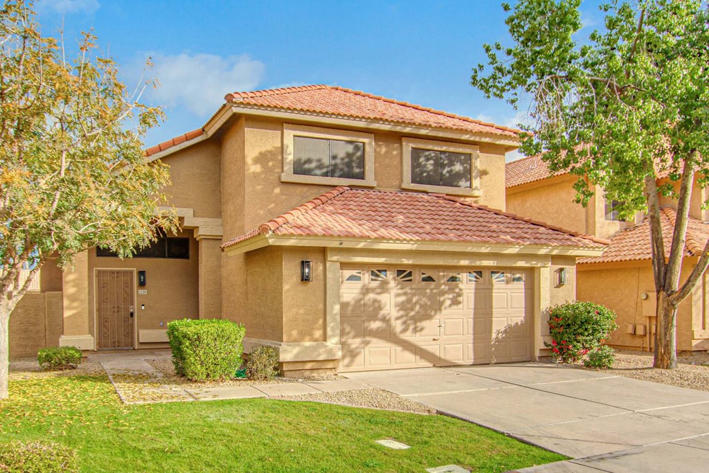 a beige house with a garage and trees