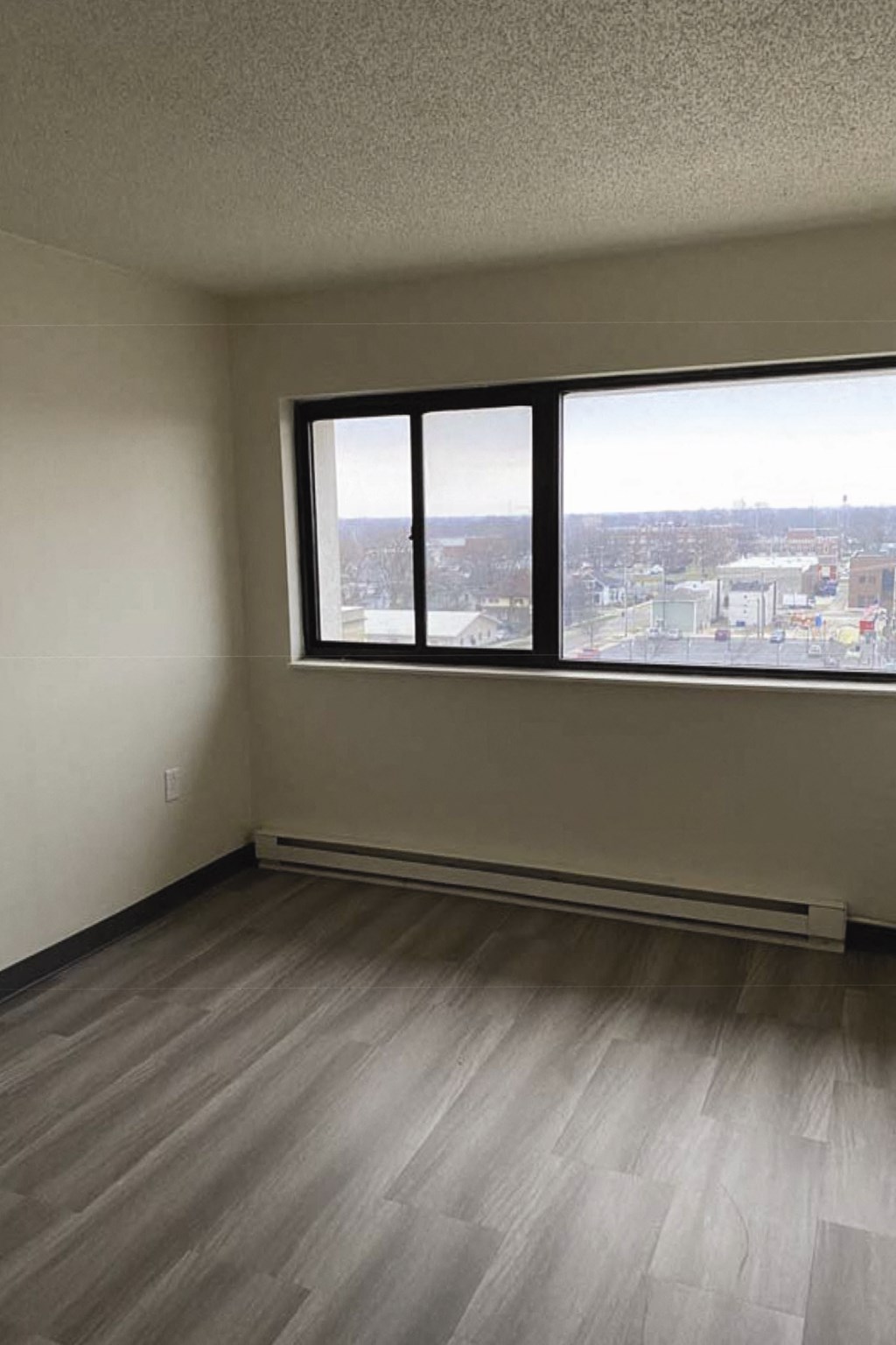 an empty room with three windows and a wooden floor