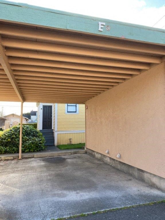 an empty garage with a roof over a driveway