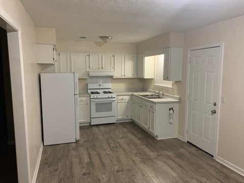 a kitchen with white cabinets and a white stove and refrigerator