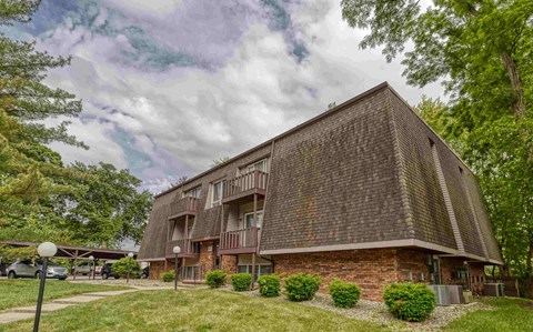 A large brick building with a sloped roof and a parking lot in front.