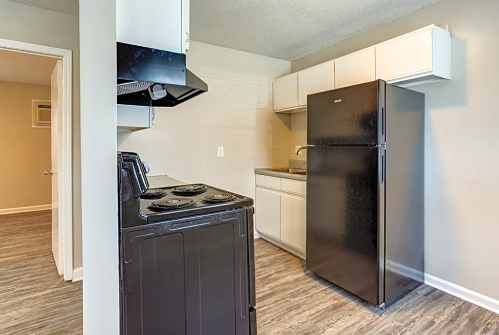 a kitchen with a black refrigerator freezer next to a stove top oven