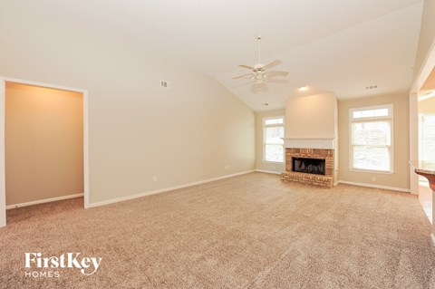 A spacious living room with a fireplace and a carpeted floor.