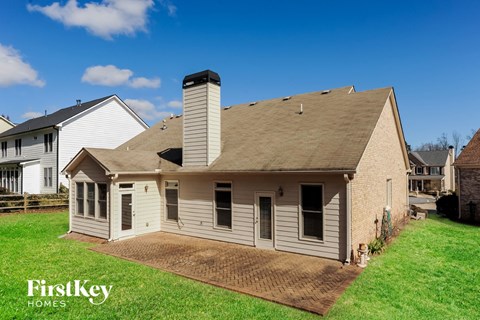 A house with a brown roof and a chimney is surrounded by a grassy area.