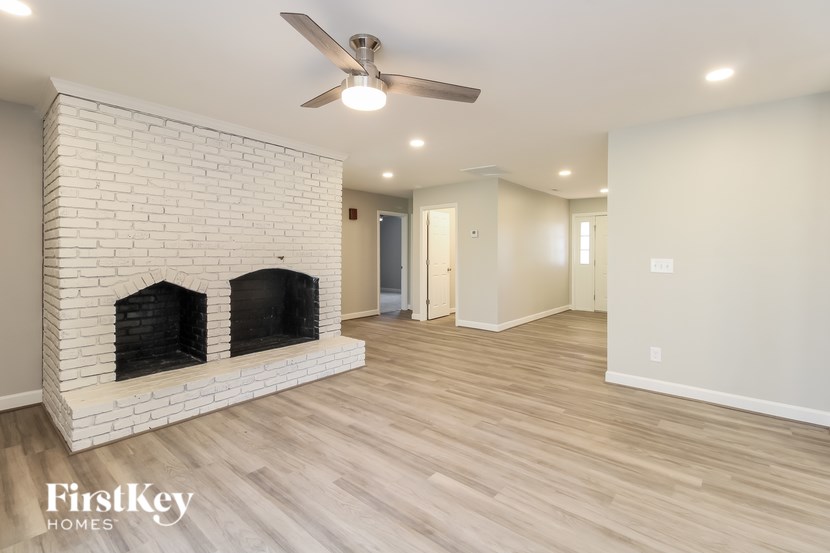 A spacious room with a fireplace and a ceiling fan.