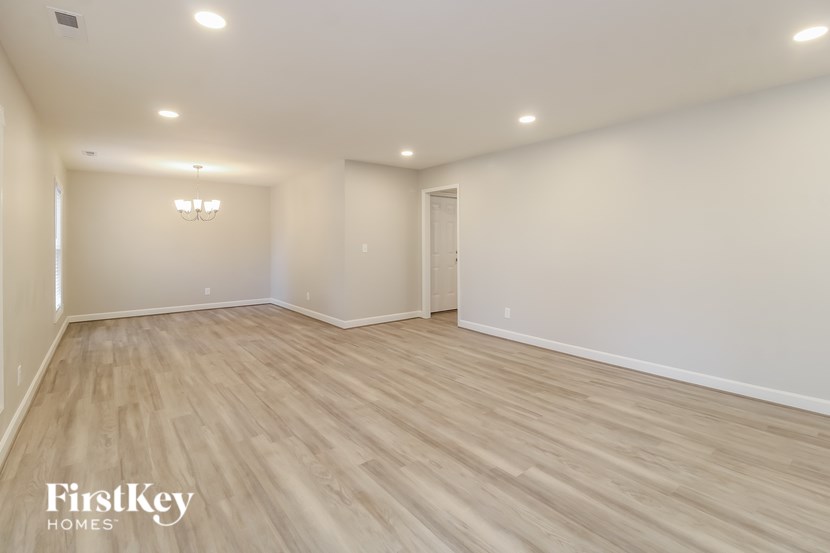 A spacious room with wooden flooring and a chandelier.