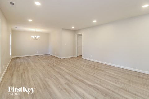 A spacious room with wooden flooring and a chandelier.