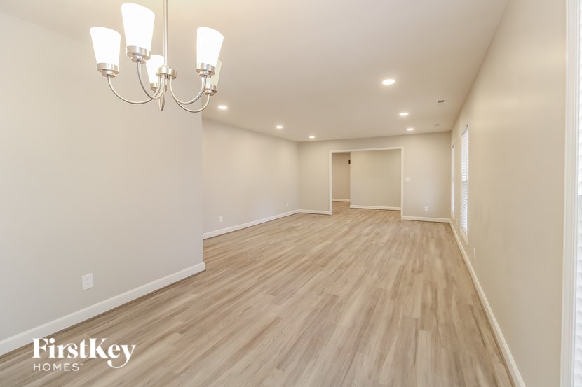 A spacious room with wooden flooring and a chandelier.