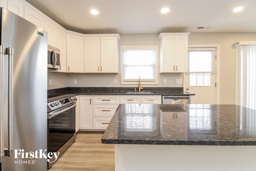 A kitchen with a black granite countertop and white cabinets.