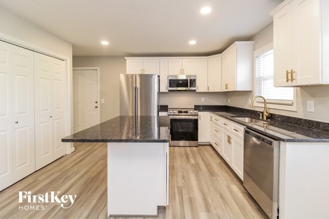 A kitchen with a refrigerator, oven, and sink.