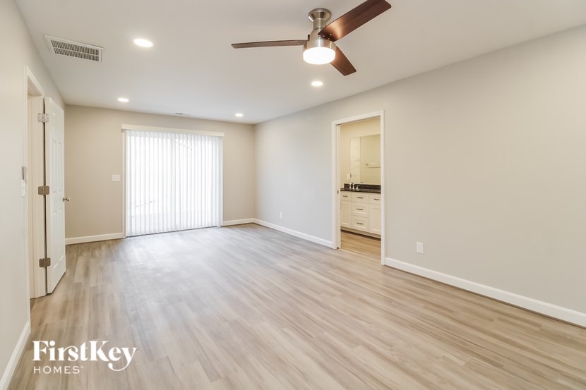 A spacious room with a ceiling fan and lighting fixtures.
