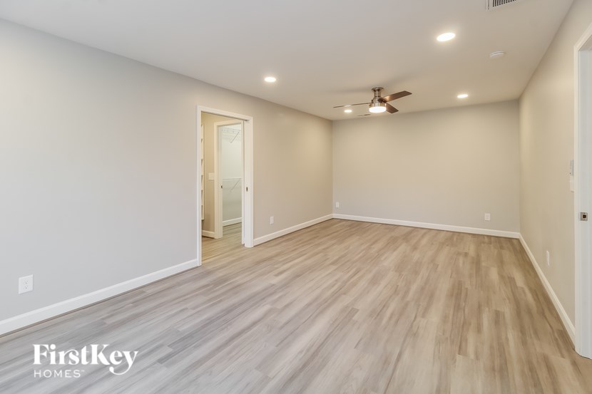 A spacious room with wooden flooring and a ceiling fan.