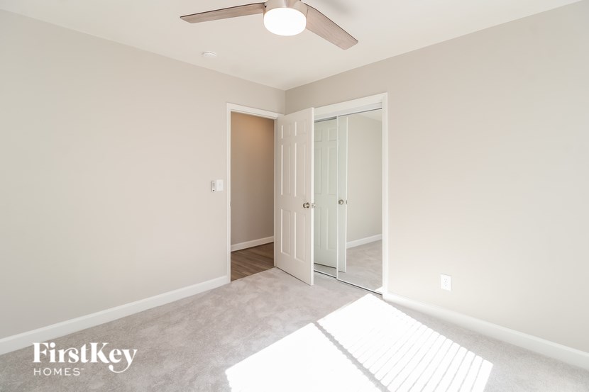 A room with a white door and a fan on the ceiling.