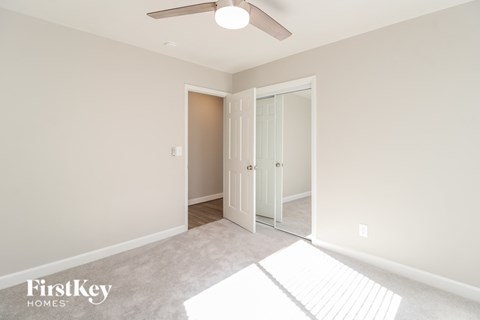 A room with a white door and a fan on the ceiling.