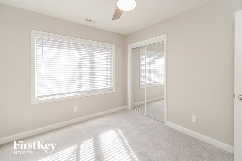 A well-lit room with a large window and a mirror on the wall.