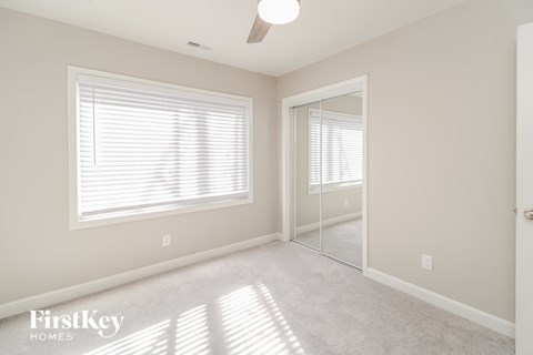 A well-lit room with a large window and a mirror on the wall.