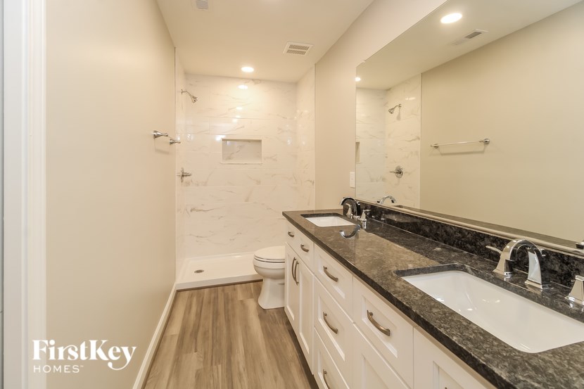 A bathroom with a marble tile shower and a white toilet.