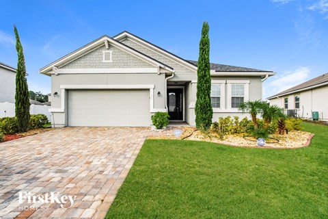 a white house with a brick driveway and a lawn