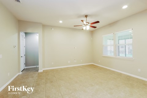 an empty living room with a ceiling fan and a door