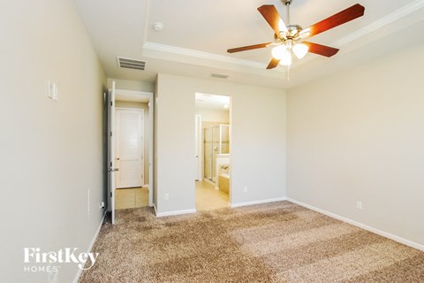 a spacious living room with carpet and a ceiling fan
