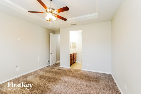 a spacious living room with white walls and a ceiling fan