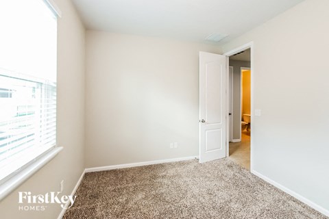 a bedroom with a carpeted floor and a door to a hallway