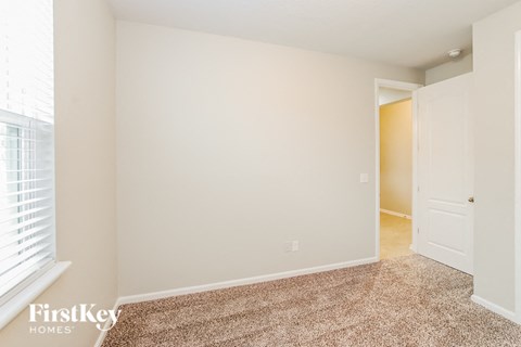 a bedroom with a door and a carpeted floor