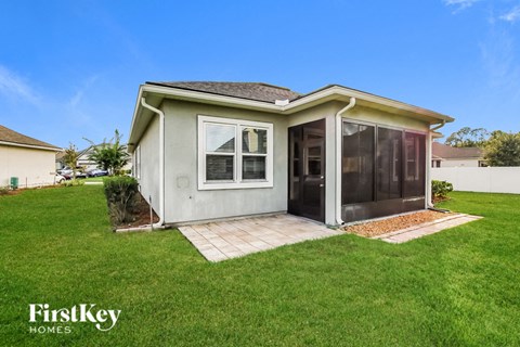 a small gray house with a patio in the grass