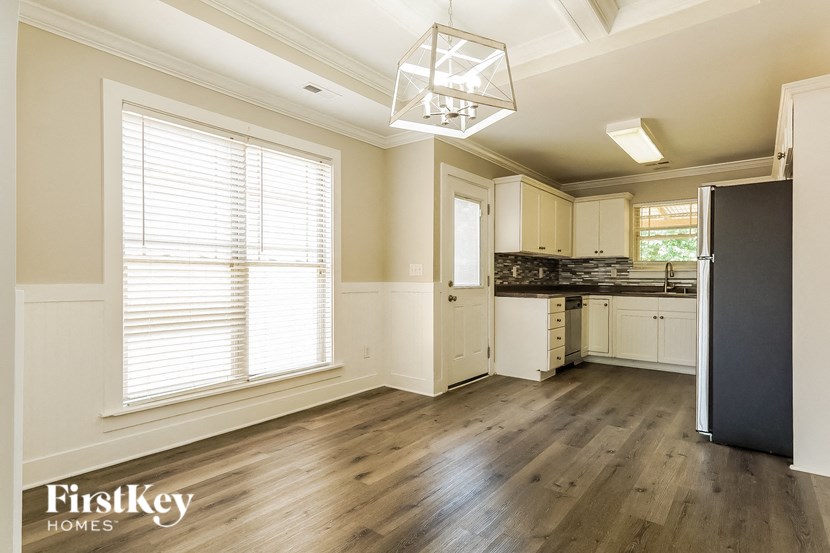 A kitchen with wooden floors and a black refrigerator.