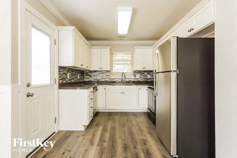 A kitchen with a black refrigerator and wooden floors.