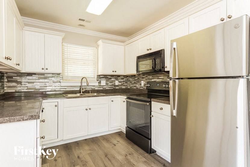 A kitchen with white cabinets and a stainless steel refrigerator.
