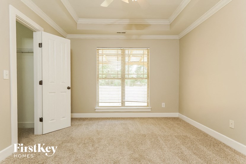 A room with a carpeted floor, a window with blinds, and a door.