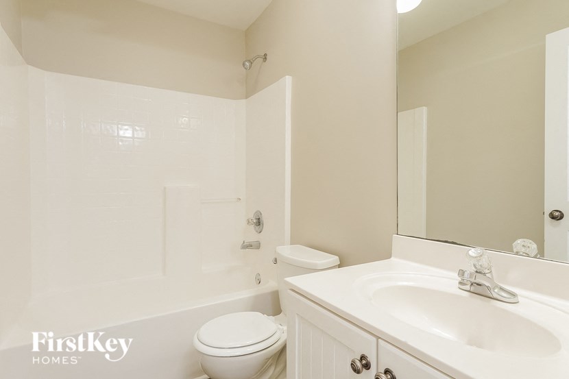 A white bathroom with a toilet, sink, and mirror.