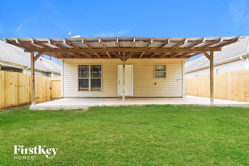 A house with a wooden pergola attached to it.