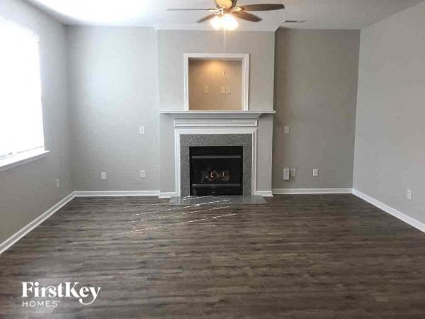 a empty living room with a fireplace and a ceiling fan