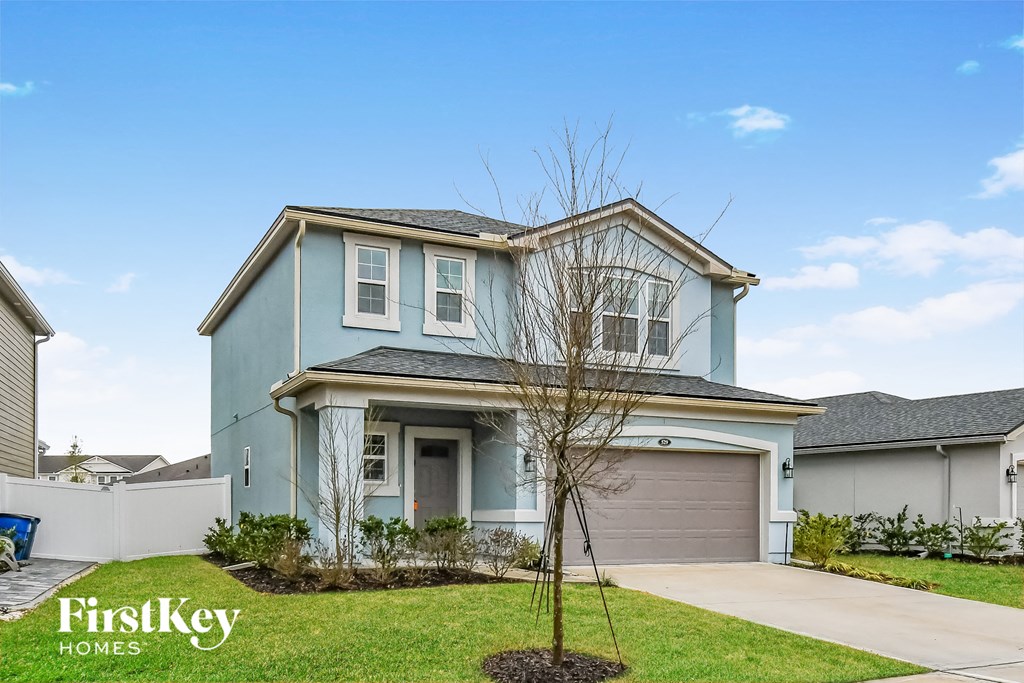 a blue house with a garage and a tree in front of it