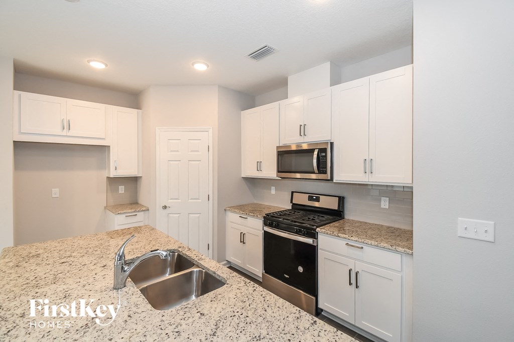a kitchen with white cabinets and granite counter tops and a sink