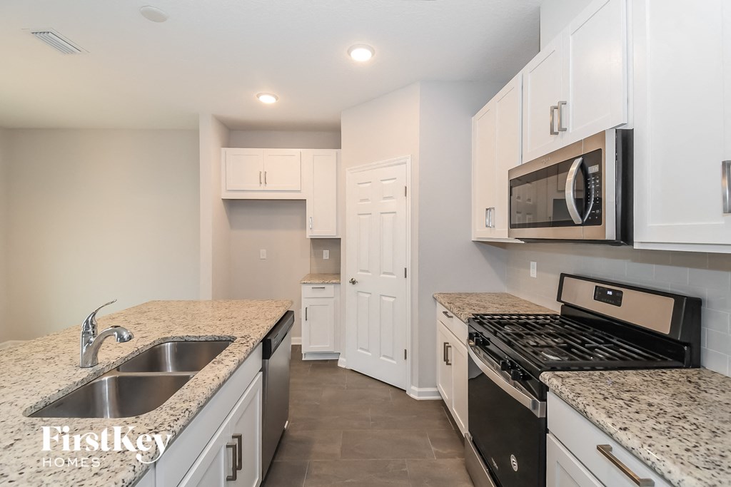 a kitchen with white cabinets and granite counter tops and a stove and microwave